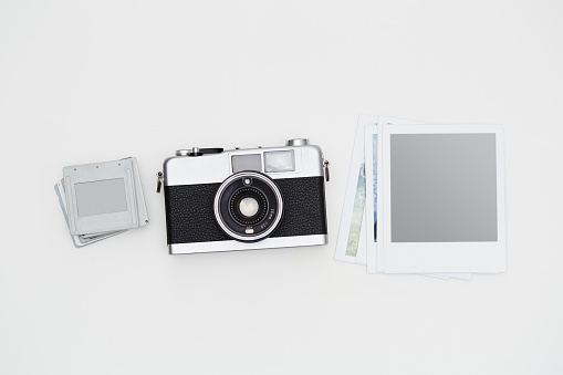 Film camera and some dia slides with blank instant photographs on white background