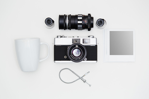Vintage SLR camera-lenses set and coffee mug with some blank polaroid-like frames on white background