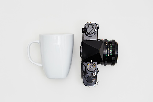 Film camera and coffee mug on white background