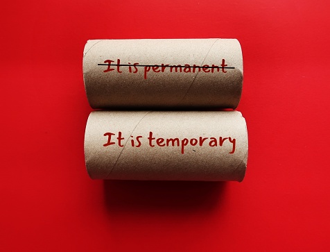 Two toilet rolls with handwritten text crossed off IT IS PERMANENT to IT IS TEMPORARY, concept of optimist vs pessimist different thinking when bad things happen
