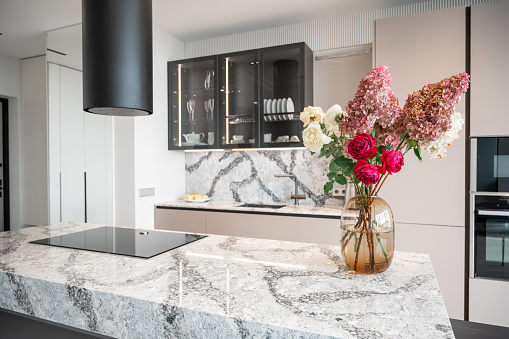 Kitchen in new luxury home with granite quartz table with bouquet of flowers