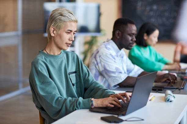 istock Side view of young classmates networking with focus on blond Asian guy 1648258673