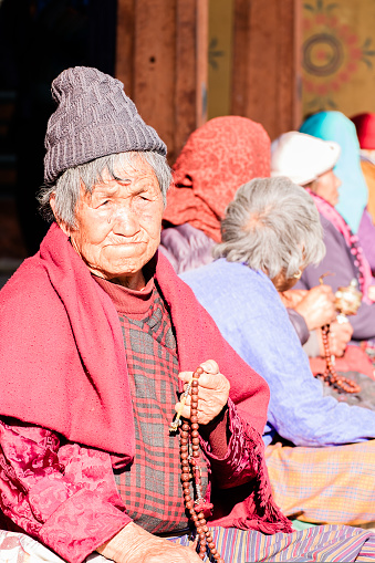 Thimphu, Bhutan - Desember 04, 2018: Old bhutanese woman praying in he Thimphu Chorten. High quality photo