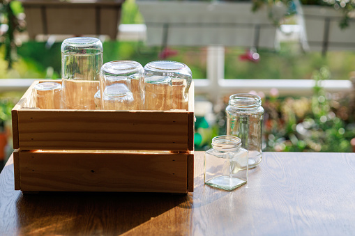 A wooden box is filled with empty glass jars, all prepared for recycling. This setup showcases a sustainable lifestyle and responsible waste management.