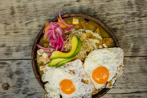 Mexican chilaquiles with fried egg, chicken and spicy green sauce traditional breakfast in Mexico