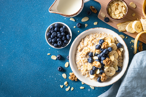 Healthy breakfast. Oatmeal porrige with berries and nuts at blue background. Top view.