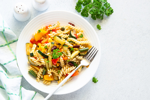 Vegan pasta with vegetables. Healthy vegetarian dish. Top view on white.