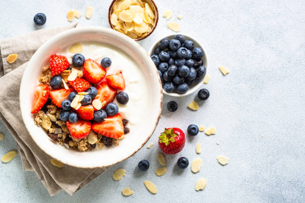 istock Yogurt with granola and fresh berries at light stone table. 1648265686