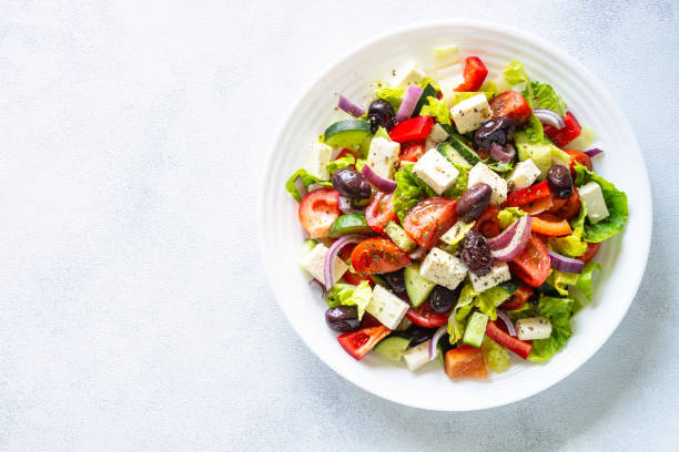 Greek salad. Vegetable salad with tomato, cucumber, feta cheese and olive oil. Top view on white stone table.