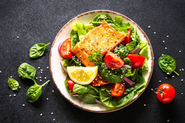 istock Green salad with salmon fillet on black. 1648270454