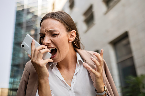 Angry businesswoman using phone shouting