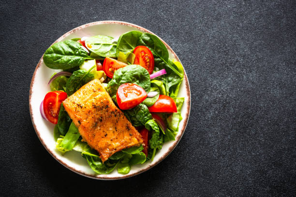 istock Green salad with salmon fillet on black. 1648280027