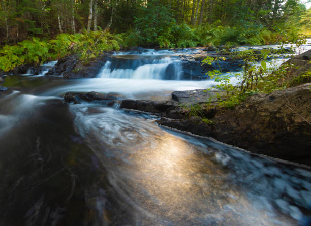 istock Sun reflecting off a pool of water below a waterfall 1648288064