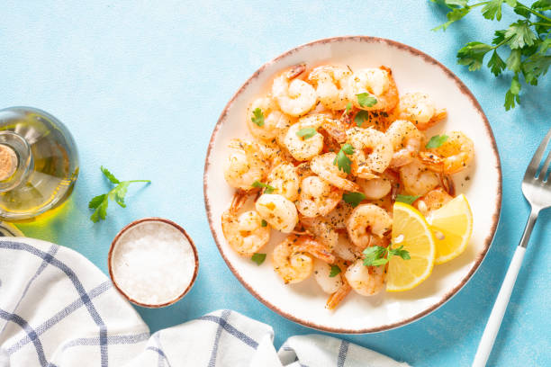 istock Fried shrimps with herbs and olive oil at blue table. 1648288635