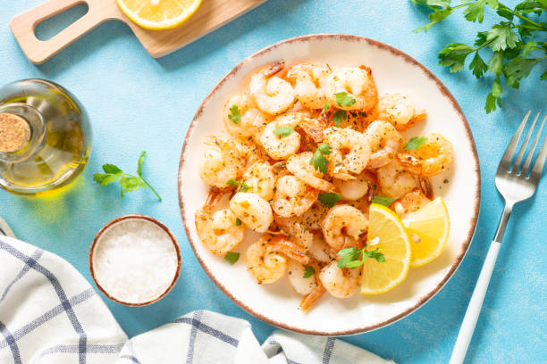 istock Fried shrimps with herbs and olive oil at blue table. 1648288644