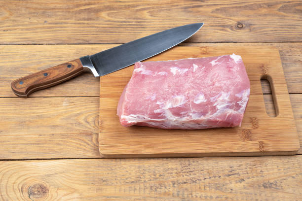istock Raw pork meat on a cutting board and a kitchen knife. 1648290830