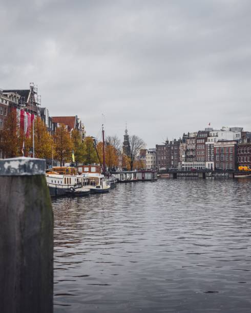широкоугольный вид на канал в амстердаме в осенний день, глядя на башню монтельбансторен - montelbaan tower стоковые фото и изображения