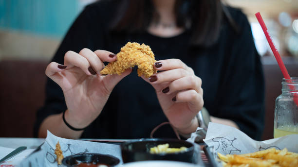 istock Young girl eats fried chicken in the mall 1648304867