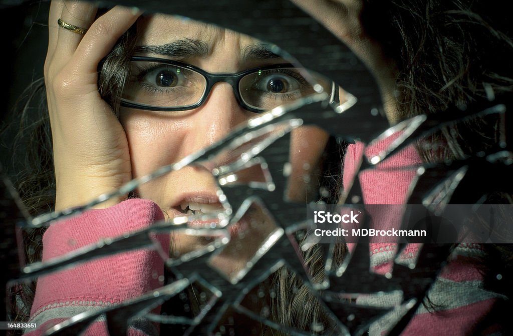 Oh no 7 years bad luck! Portrait of a desperate woman looking at a broken mirror Cracked Stock Photo