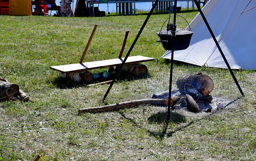 A close up on some bread baked on a metal or brass pan hanging from a special metal frame seen in the middle of a medieval camp spotted on a sunny summer day during a historical reenactment