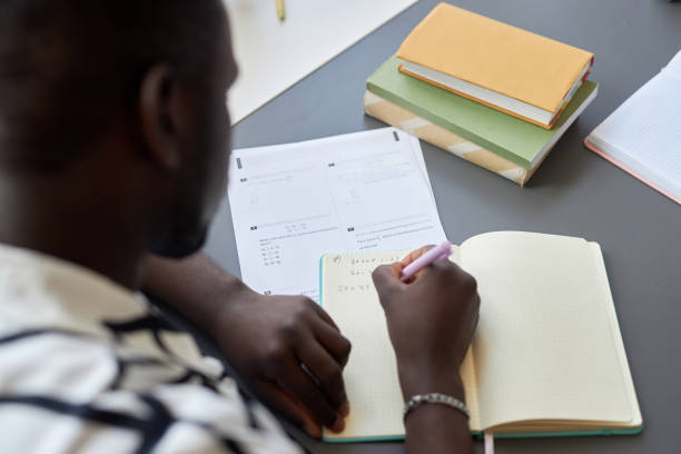 istock Close-up of young black man writing down formula or equation in copybook 1648339627