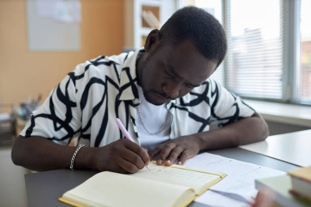 istock Serious African American male student bending over open copybook 1648340609