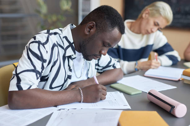 istock Serious African American guy making notes or putting ticks on test paper 1648341149