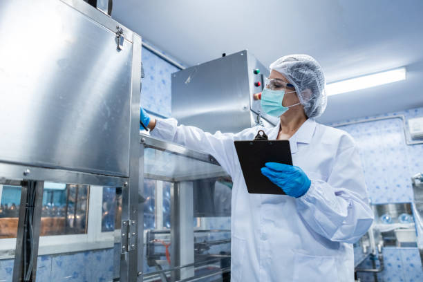 istock Female worker using tablet checking quality drinking water before process of filling water into plastic bottles to bring out to consumers. Water bottles on production line of factory. 1648343351
