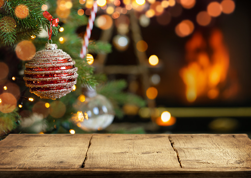 Empty wooden table on Christmas ornaments background with fireplace.