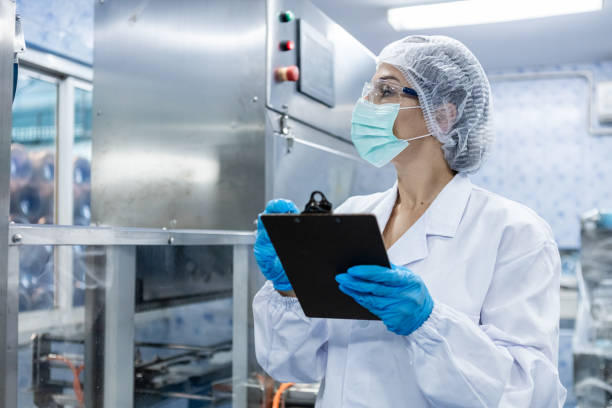 istock Female worker take note checking quality drinking water before process of filling water into plastic bottles to bring out to consumers. Water bottles on production line of factory. 1648346037