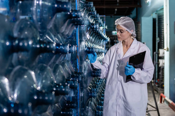 istock Female worker holding clipboard checking quality of large drinking water tanks before process of filling water into plastic bottles to bring out to consumers. Water bottles on production line of factory. 1648352027
