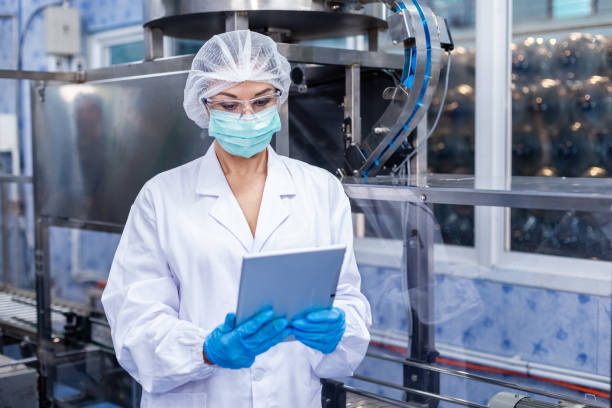 istock Female worker looking information on tablet checking quality drinking water in production line of factory. 1648355168