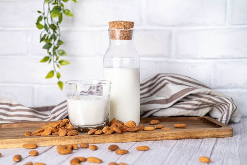 Almond milk in glass bottle and almonds on the kitchen table.