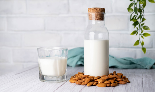 Almond milk in a bottle surrounded by almonds.