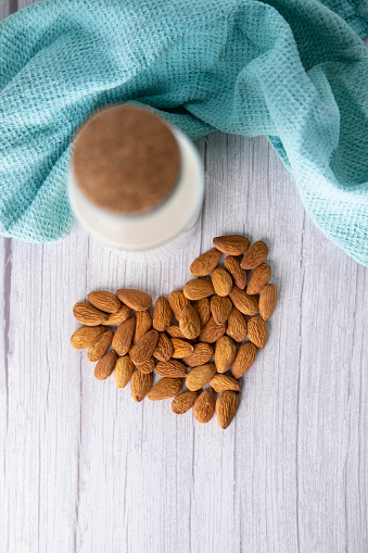 Almonds in heart shape and a bottle of almond milk. Organic alternative milk.