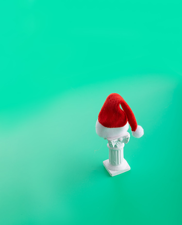 Santa claus hat on a white column on a green background. Ancient Greece aesthetic concept