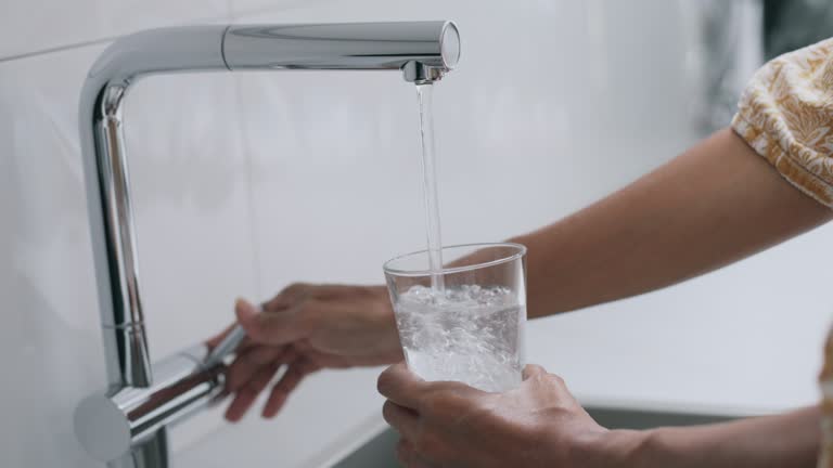 LD Woman pouring a glass of water in the kitchen