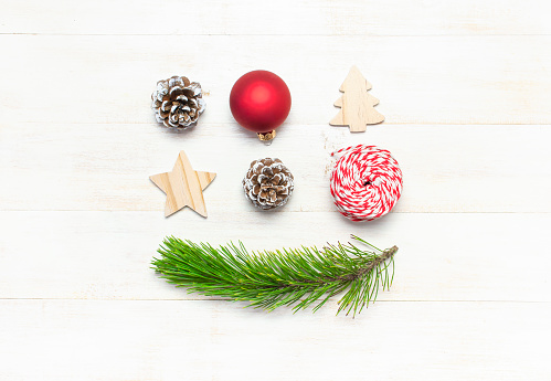 Christmas composition. New Year's wooden toys, fir cones, pine branch, red ball, gift twine on white wooden table Flat lay top view copy space. Christmas winter decoration Nature New Year concept
