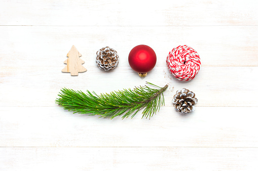 Christmas composition. New Year's wooden toys, fir cones, pine branch, red ball, gift twine on white wooden table Flat lay top view copy space. Christmas winter decoration Nature New Year concept