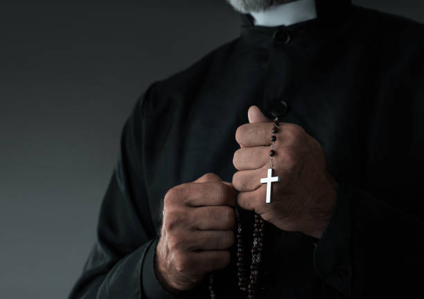 Close up of a priest holding rosary and praying stock photo