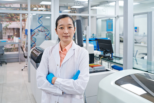 Portrait of confident female scientist standing with arms crossed in laboratory