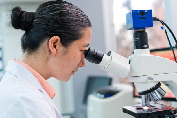 istock Side view of female scientist looking through microscope while working in laboratory 1648451659