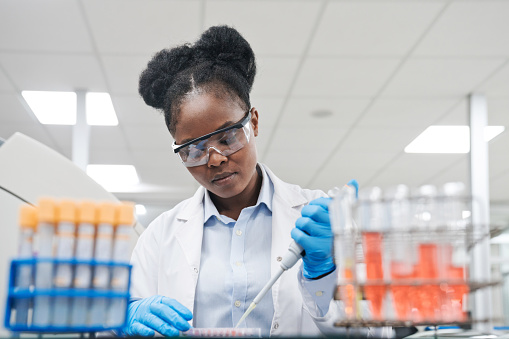 Medical Science Laboratory: Portrait of Beautiful Black Scientist Looking Under Microscope Does Analysis of Test Sample. Ambitious Young Biotechnology Specialist, working with Advanced Equipment