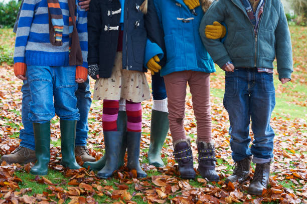 niños de pie juntos en otoño las hojas - autumn women leaf scarf fotografías e imágenes de stock