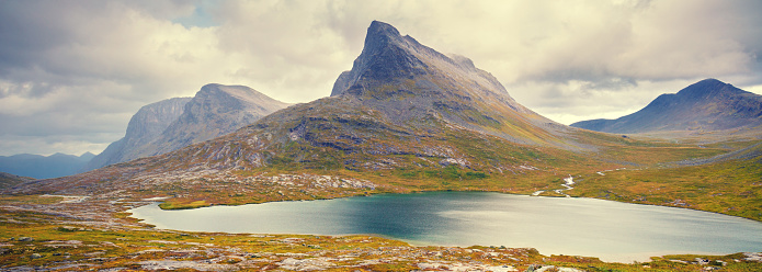 Mountain landscape. Rocky shore of mountain lake in rainy autumn morning. Beautiful nature of Norway. Horizontal banner