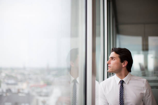 empresario mirando por la ventana de oficina - looking through window front view business looking at view fotografías e imágenes de stock