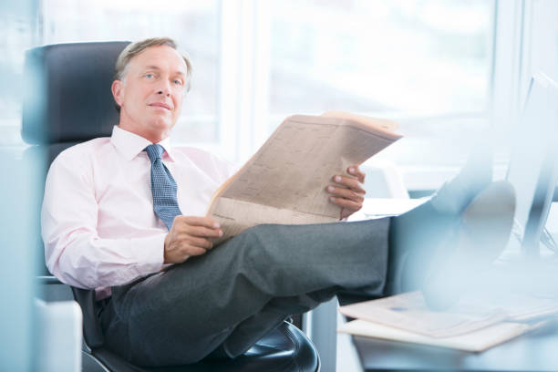 istock Businessman reading newspaper in office 164852132