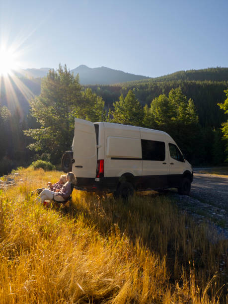 istock Mature couple relax with drinks beside campervan 1648523849