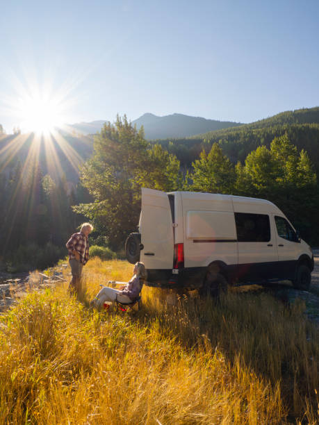 istock Mature couple relax with drinks beside campervan 1648524374