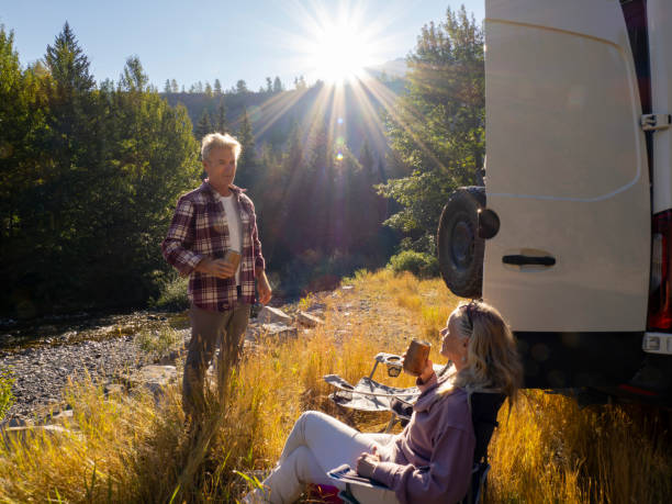 istock Mature couple relax with drinks beside campervan 1648524376